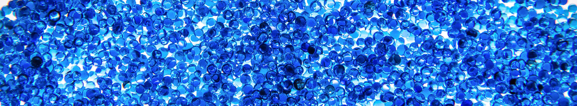 A large pile of vibrant blue resin micro-beads spread out on a light table.